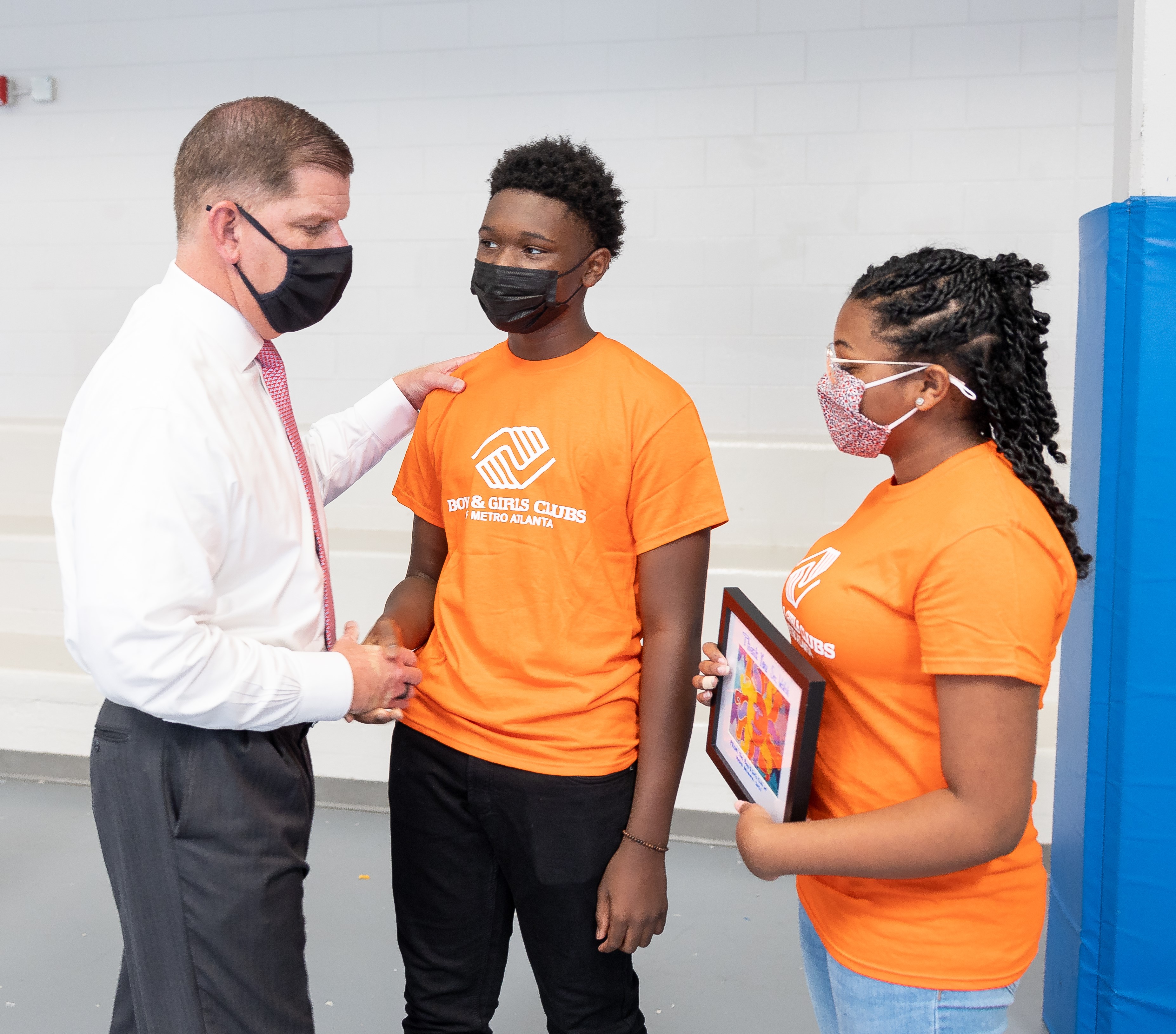 Secretary Walsh stands with two grantees
