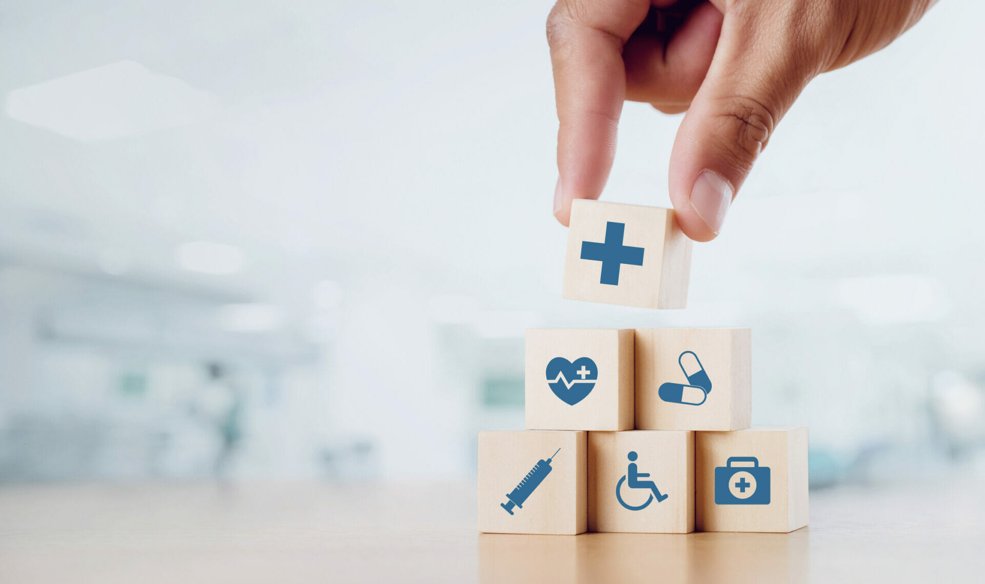 Close up man hand arranging wood block with healthcare medical icon on hospital background.
