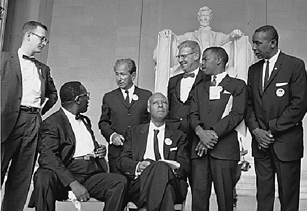 Black-and-white photo of seven March on Washington leaders including A. Philip Randolph and John Lewis in front of the Lincoln Memorial.