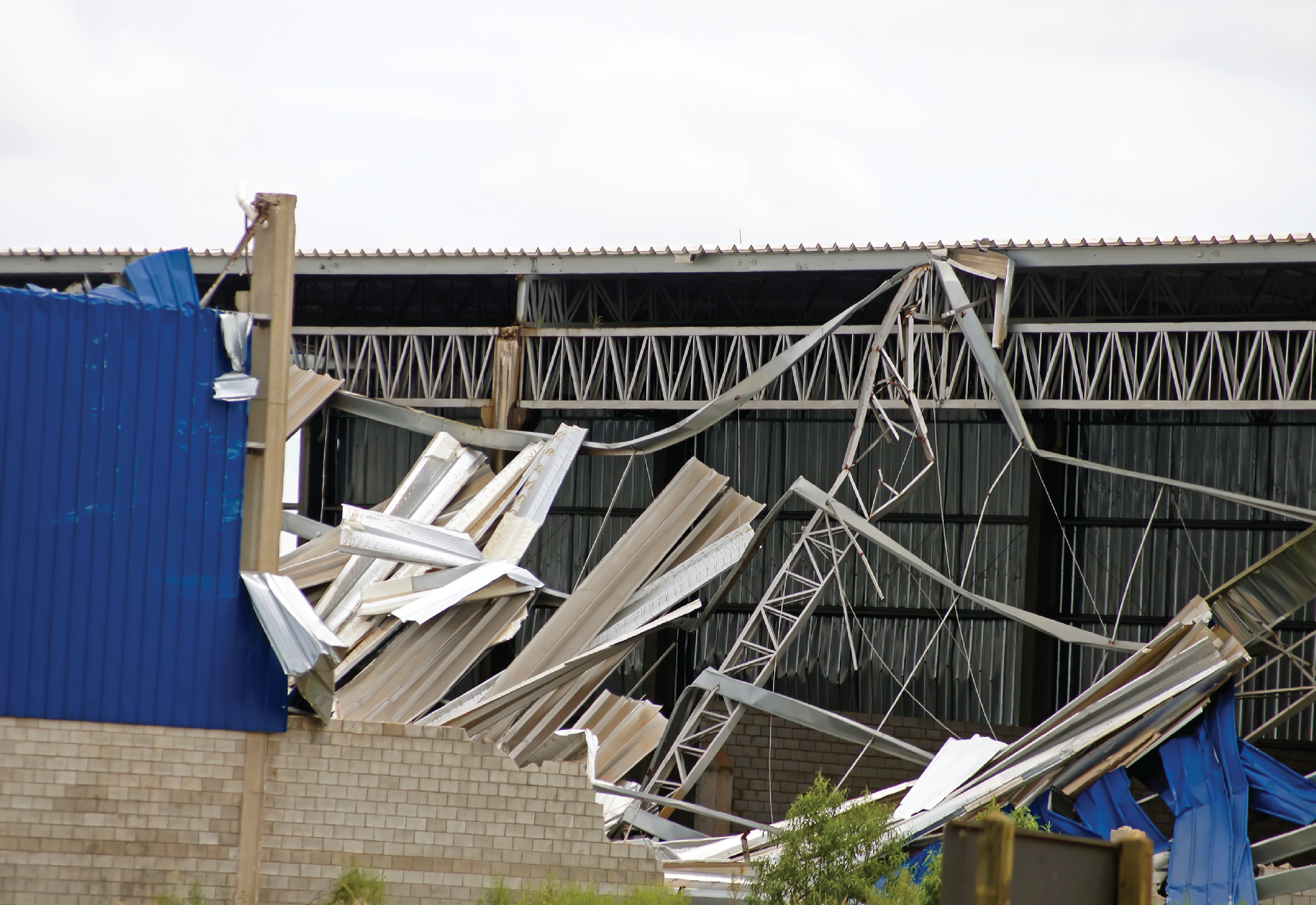 Visible wind damage in the wake of a storm. A roof and siding have been ripped from a building.