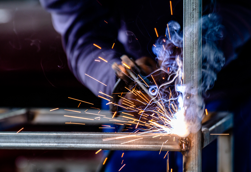 Close-up of a worker welding. The hot metal glows and sparks fly.