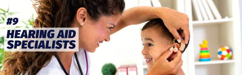 A medical worker adjusts a hearing aid for a small boy.