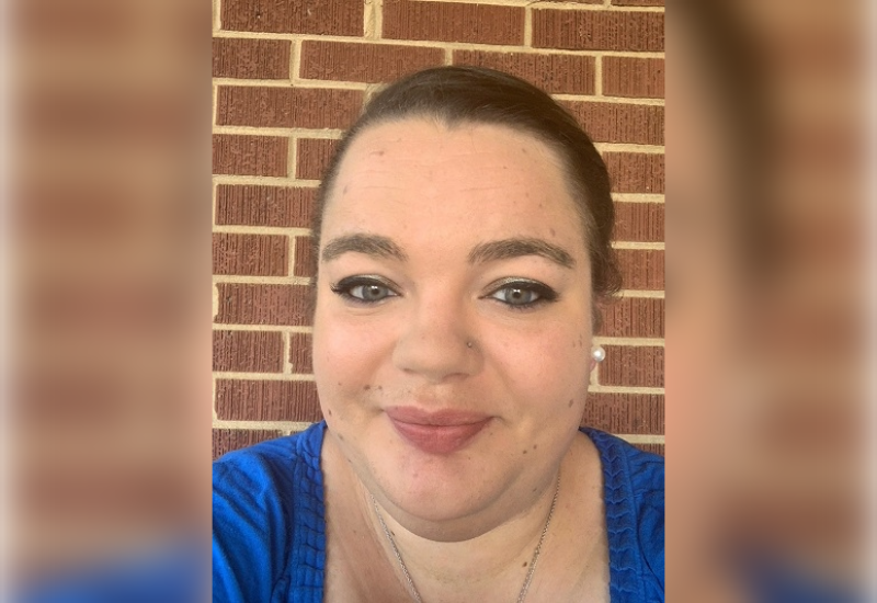 Headshot of Melyssa Scott, smiling in front of a brick wall