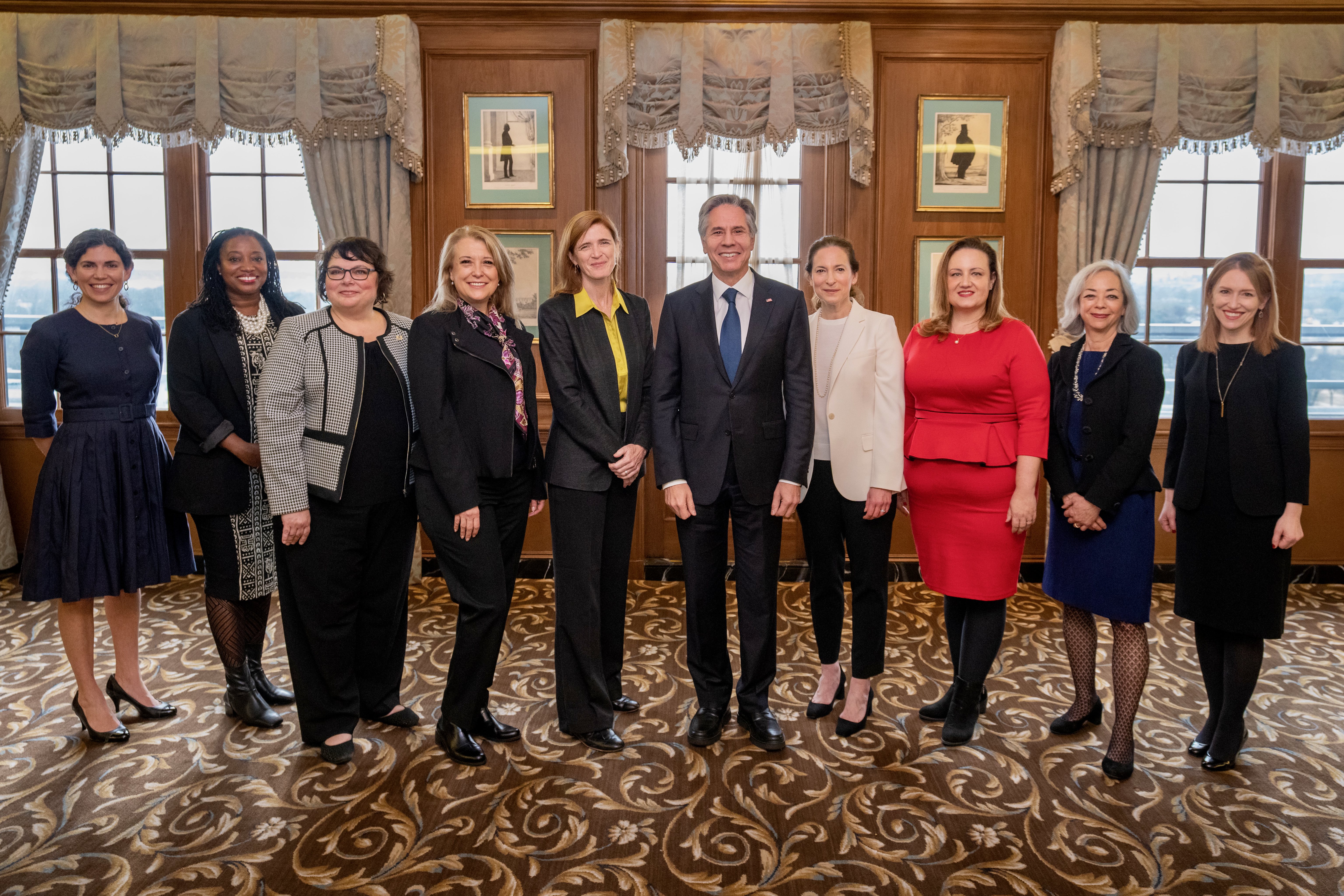 Thea Lee standing in a group with Secretary of State Blinken and USAID Administrator Power in an opulent room.