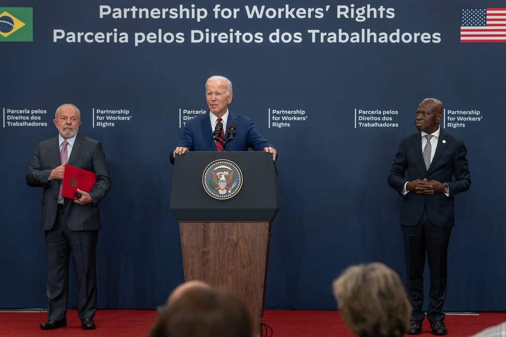 President Biden stands at a podium with Brazilian President Lula and ILO Director-General Houngbo by his side, the words
