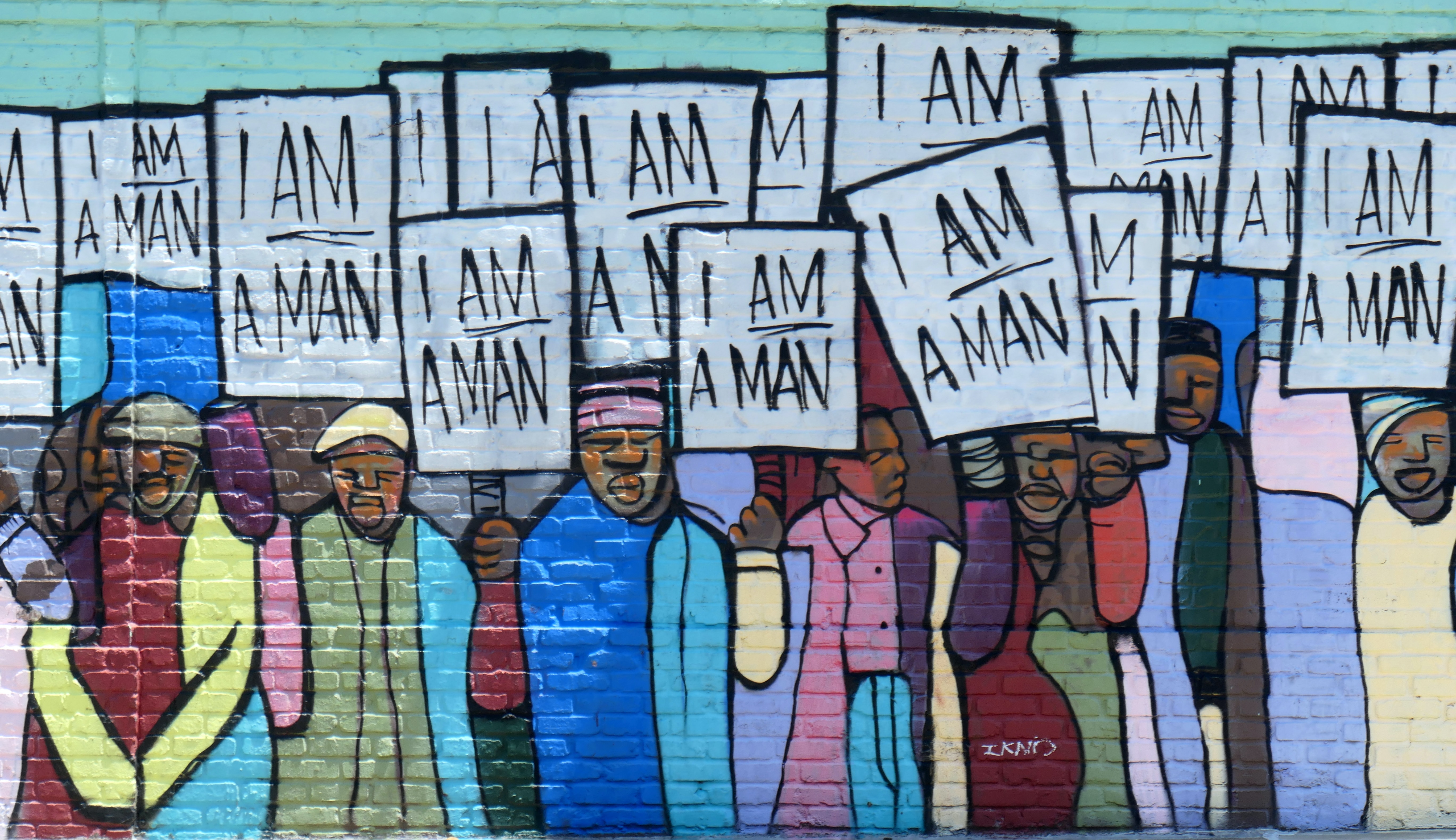 Colorful mural recreating a 1968 black and white photograph of Black workers in Memphis holding signs that read
